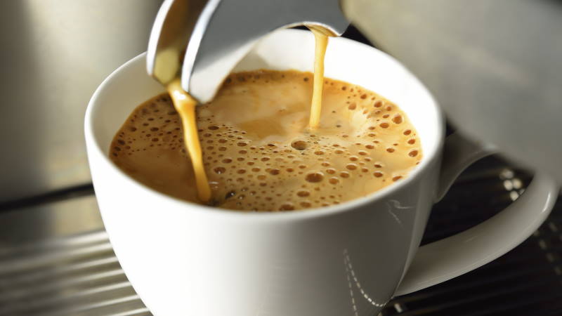 Une tasse de café remplie par une machine expresso.